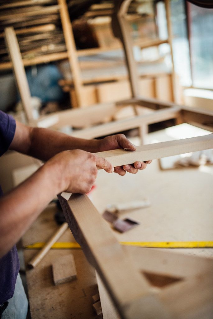 A craftsman assembling a wooden chair frame by hand