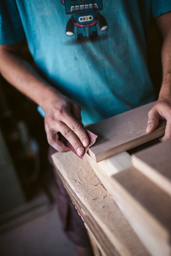 Sanding a wooden panel by hand in a workshop